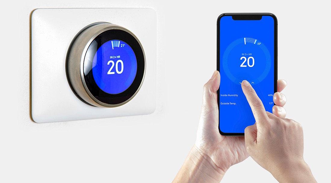 Person using a smart phone application with a wireless smart thermostat.