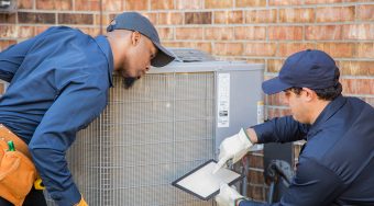 Multi-ethnic team of blue collar air conditioner repairmen at work.  They prepare to begin work by gathering appropriate tools from their tool box.