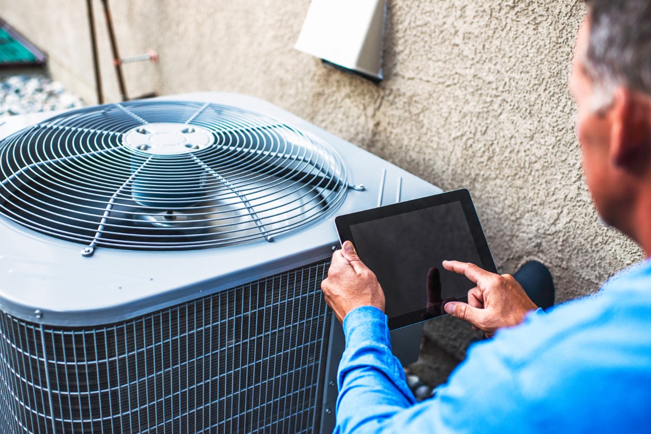 Maintenance man using a tablet to inspect air conditioning unit