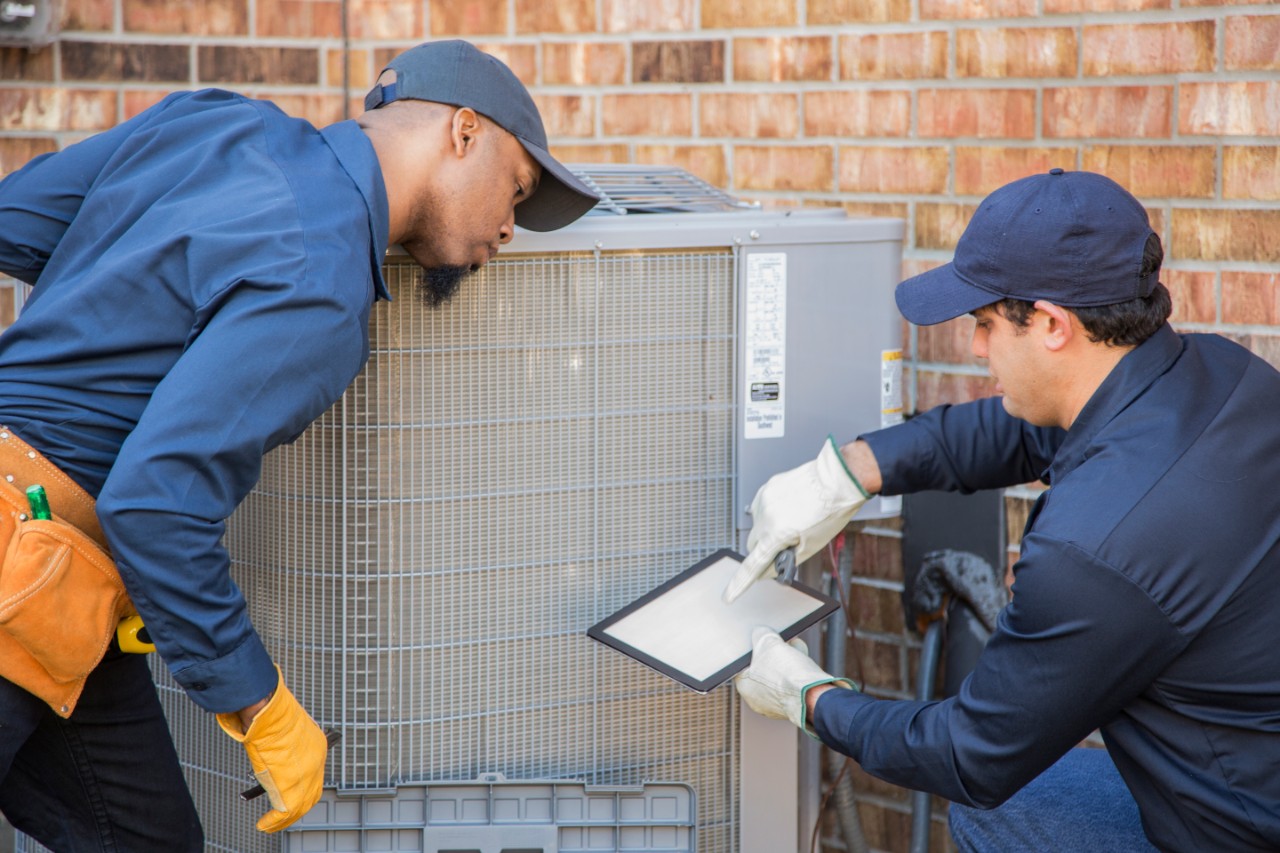 Multi-ethnic team working on air conditioner.